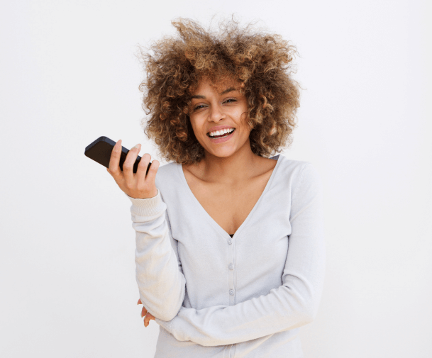 Smiling girl with curly hair holding a mobile phone.